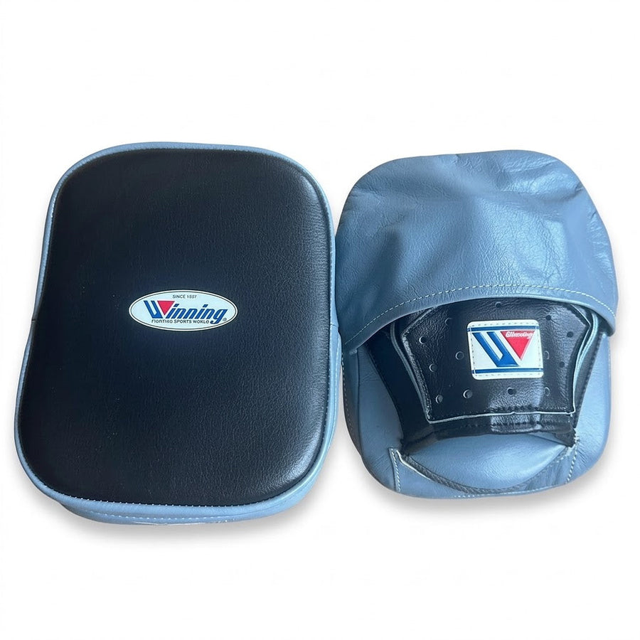 Winning focus mitts with black curved striking face and light gray-blue back, left and right pair shown