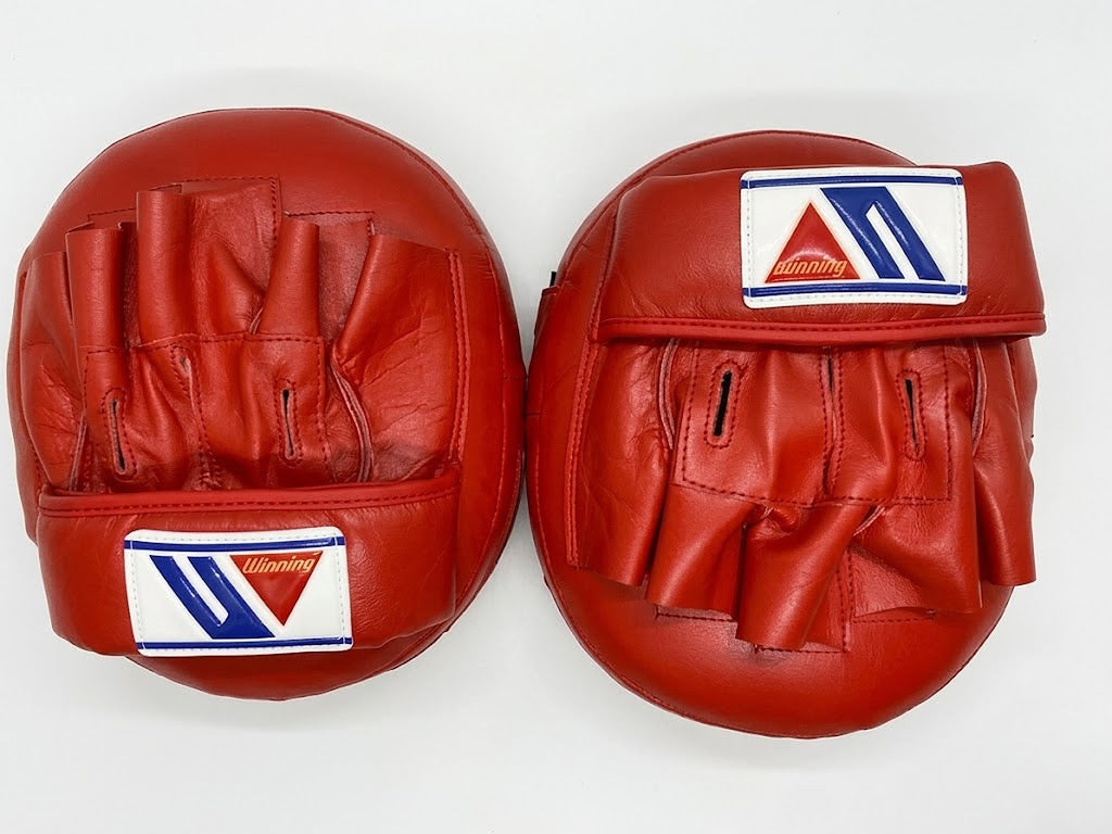 Winning solid red curved focus mitts with a deep padded striking face, pair shown from the front - palm side