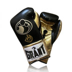 Grant black lace-up boxing gloves showing metallic gold palms, with matching black headgear and groin guard - side view