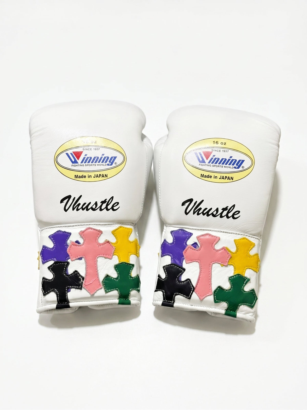 Winning white boxing gloves with multicolor cross patches on the cuff and a sample script name print