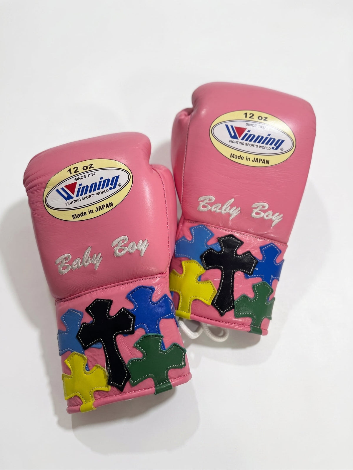 Winning pink lace-up boxing glove with multicolor cross patches around the cuff and wrist area - palm and closure detail