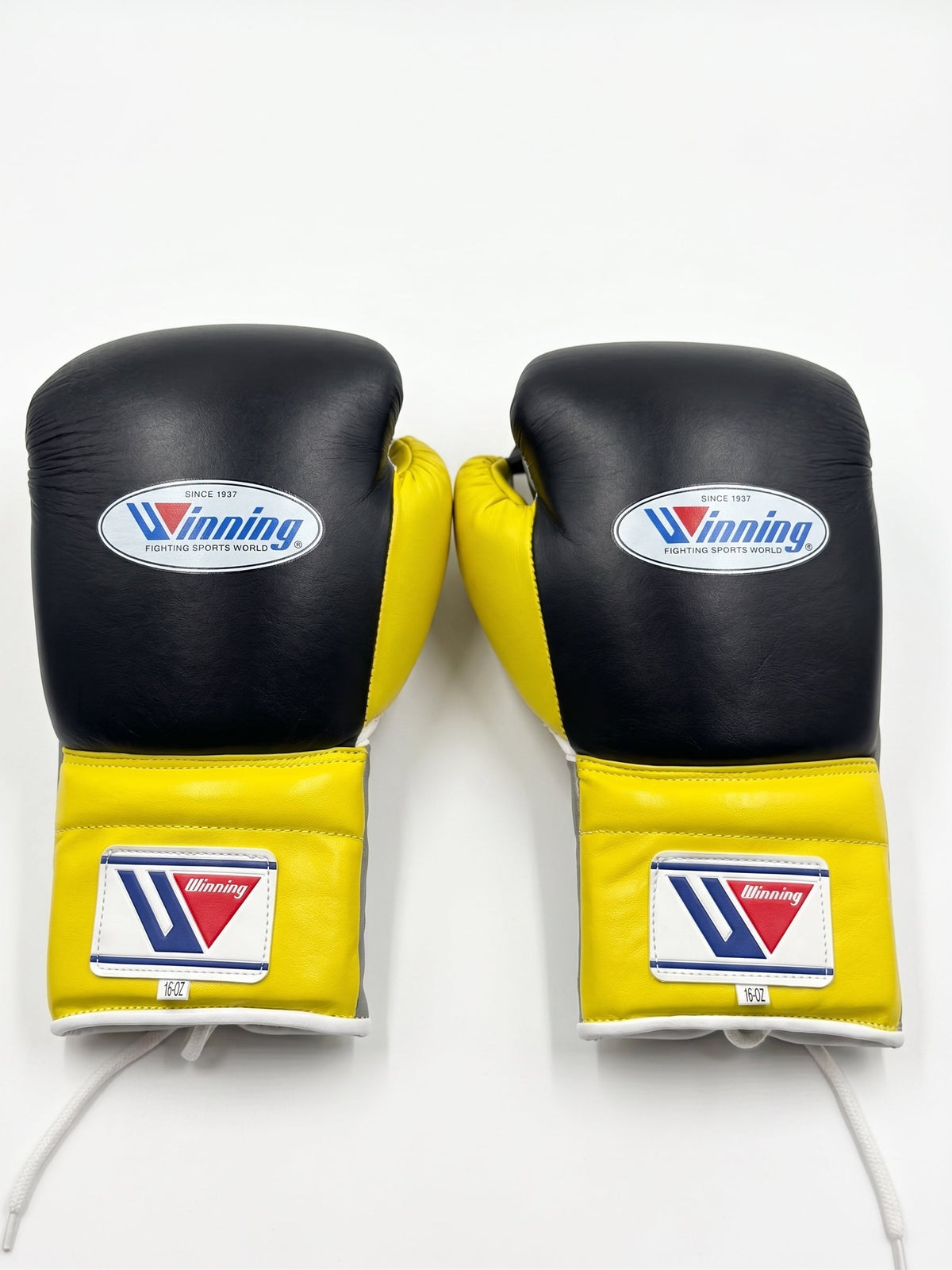 Winning black boxing gloves with gray palm and bright yellow cuff, laced up at the wrist - side view
