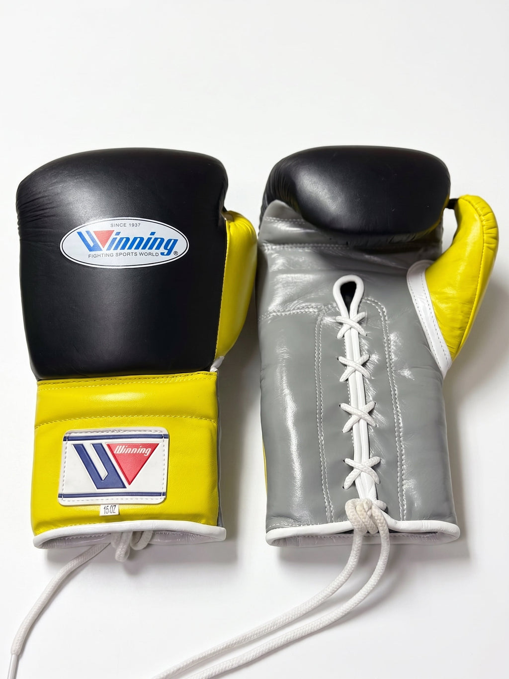 Winning black boxing gloves with gray palm and bright yellow cuff, laced up at the wrist - alternate angle