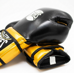 Cleto Reyes black and gold boxing gloves stacked, showing the gold wrist strap and logo