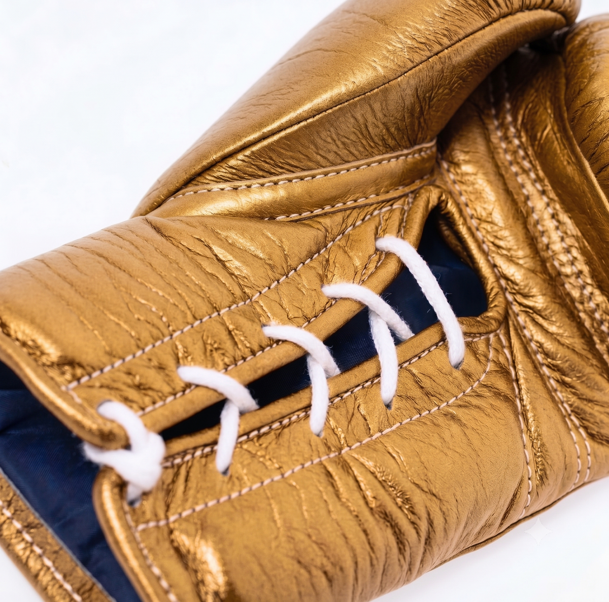 Winning MS-600 lace-up boxing glove in full metallic gold leather reflecting light across the back - side view