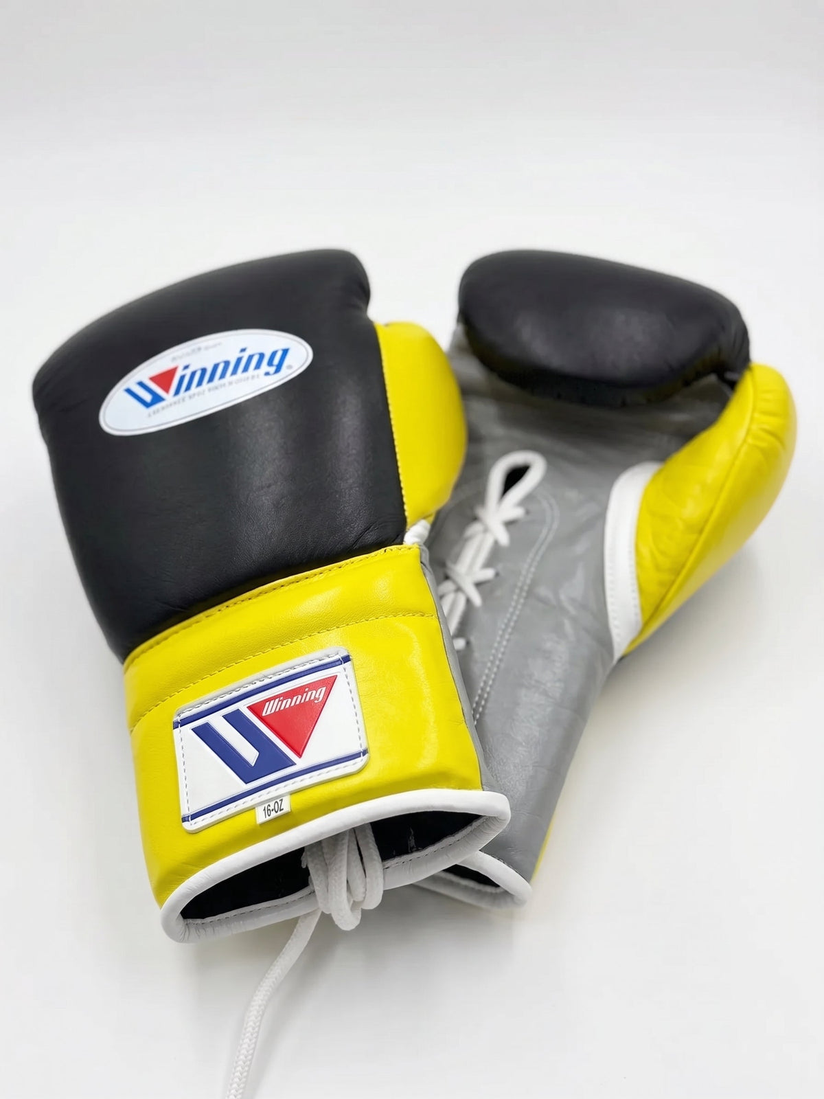 Winning black boxing gloves with gray palm and bright yellow cuff, laced up at the wrist - palm and closure detail