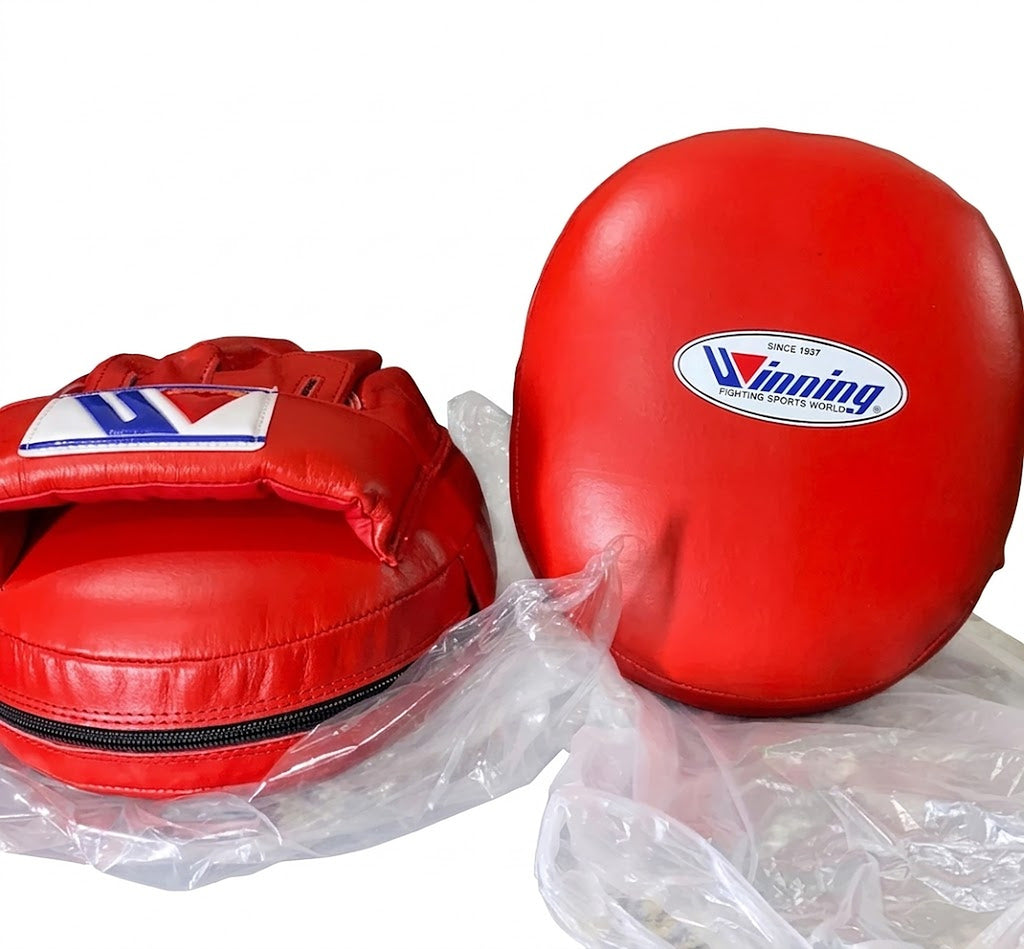 Winning solid red curved focus mitts with a deep padded striking face, pair shown from the front - side view