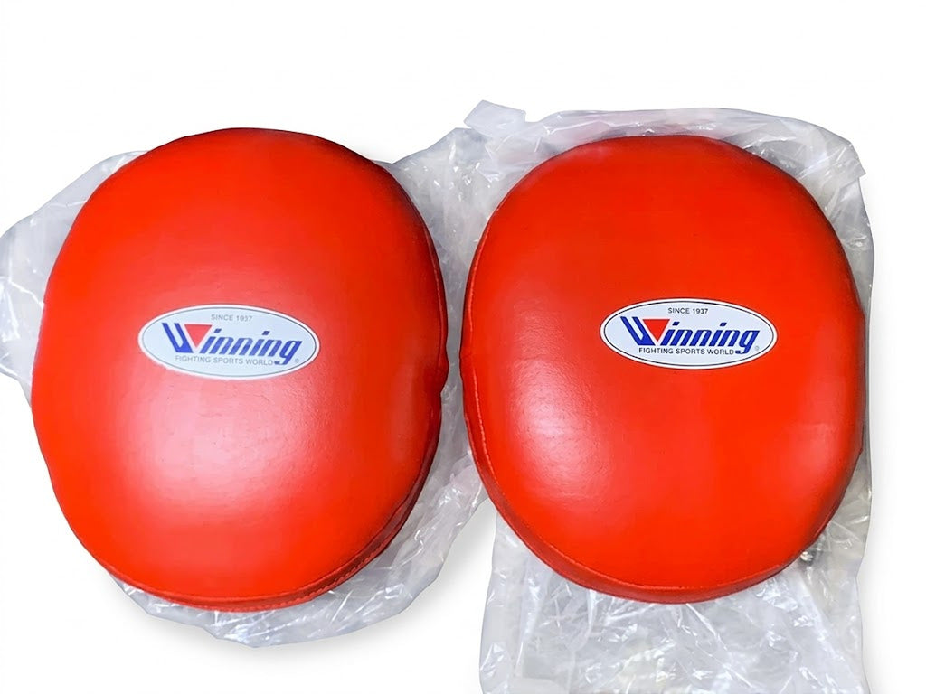 Winning solid red curved focus mitts with a deep padded striking face, pair shown from the front - alternate angle