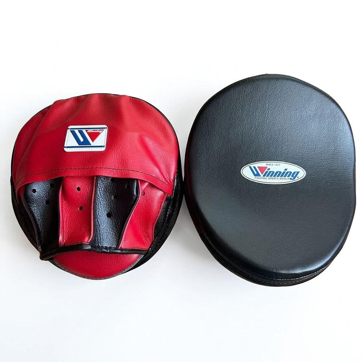 Winning two-tone punch mitts with black curved striking face and red palm, shown as a side-by-side pair